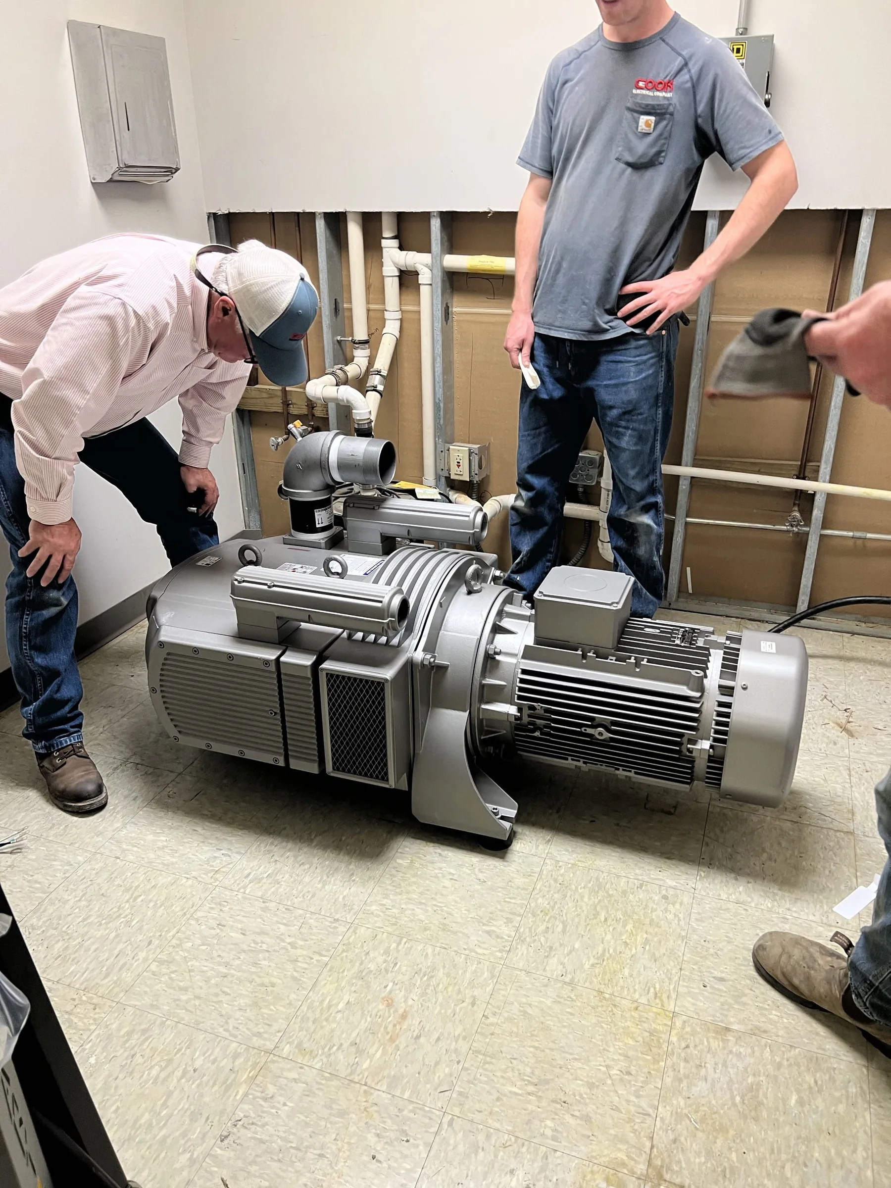 Crew inspecting a large industrial motor and blower assembly.