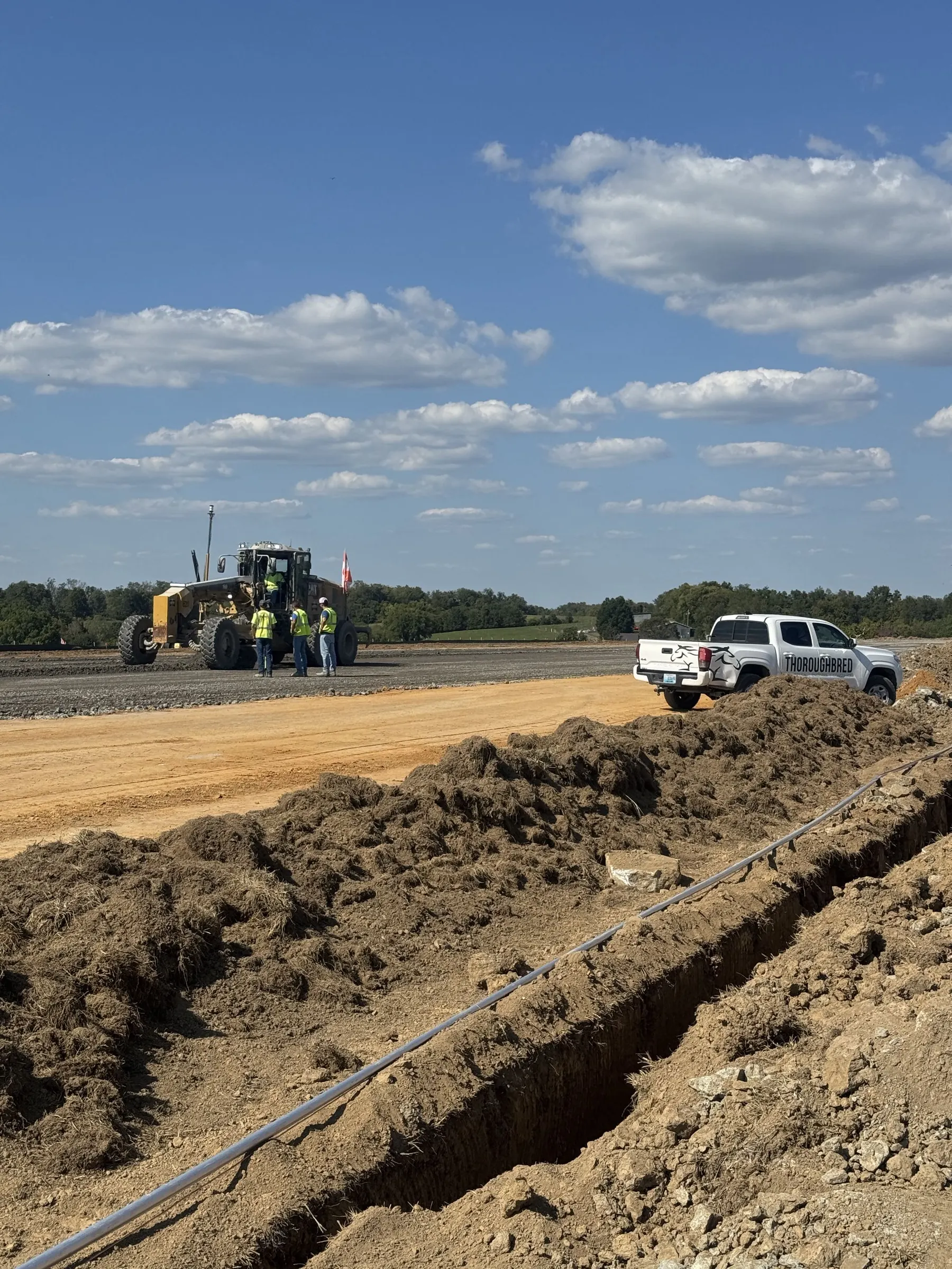 Active commercial construction site with excavation equipment and open trenching.